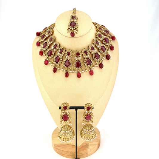 Necklace set with maroon and gold stone work and maroon beads. Set includes necklace, tikka and earrings. Prefect for Indian weddings, parties and special occasions. Latest 2022 fashion. High end Indian fashion jewellery with top quality stones and beads.