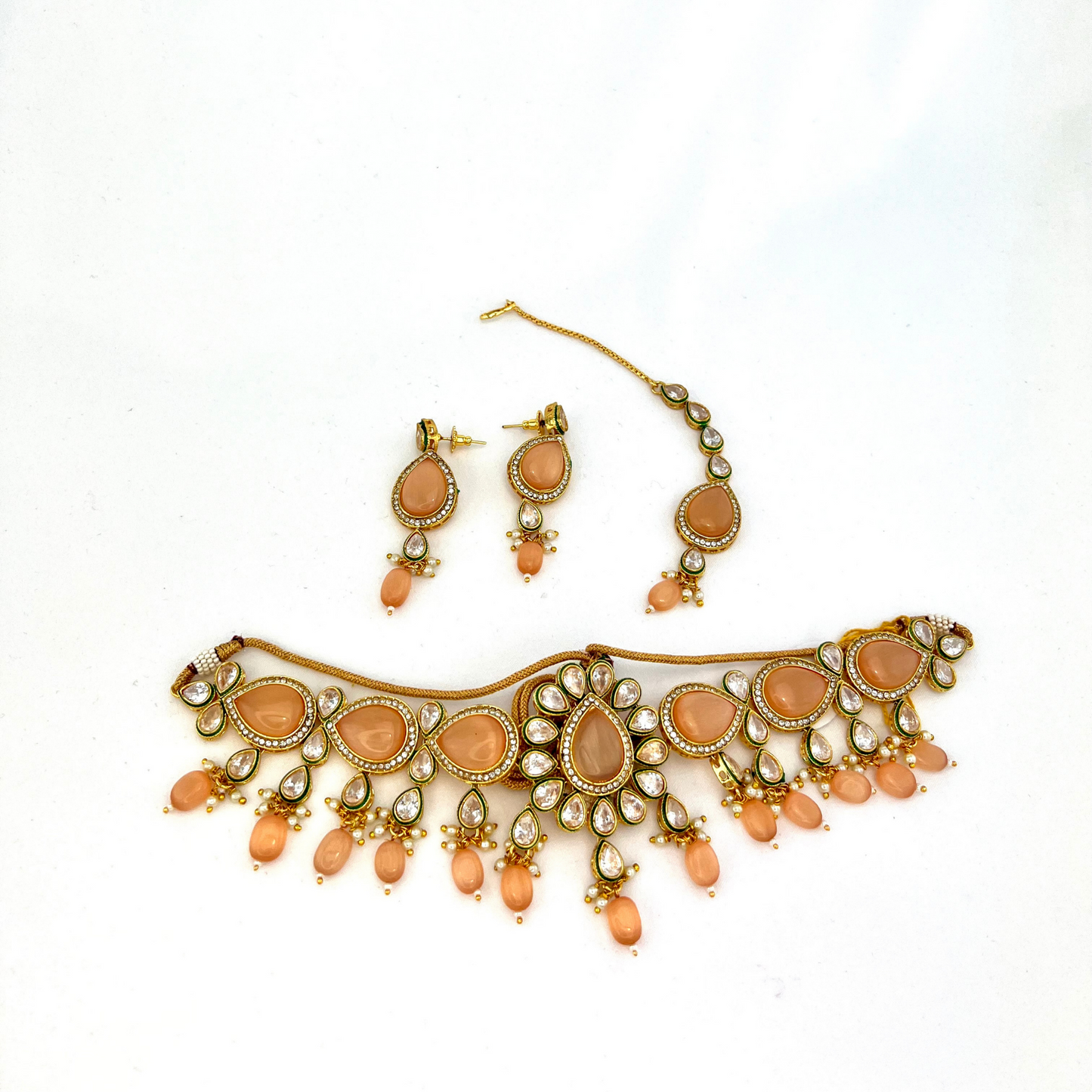 Choker set with peach, clear stones and peach beads. Set includes choker, tikka and earrings. Prefect for Indian weddings, parties and special occasions. Latest 2022 fashion. High end Indian fashion jewellery with top quality stones and beads.