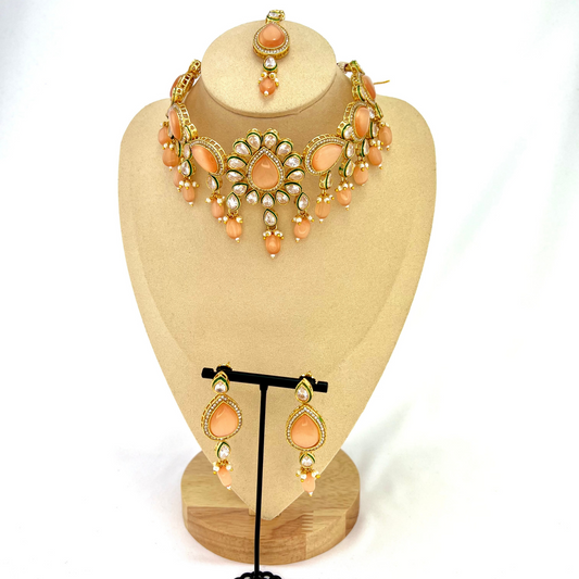 Choker set with peach, clear stones and peach beads. Set includes choker, tikka and earrings. Prefect for Indian weddings, parties and special occasions. Latest 2022 fashion. High end Indian fashion jewellery with top quality stones and beads.